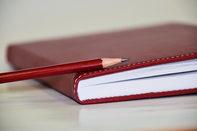 赤いノートと鉛筆。お金日記を書くイメージ
